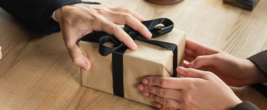 Hands exchanging a corporate gift, symbolizing brand awareness and customer loyalty.